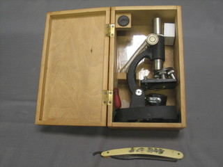 A child's microscope contained in a wooden box and a cut throat razor