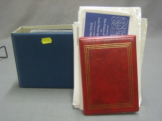 A green album of various first day covers and a plastic bag containing a small red album of postcard stamps and first day covers