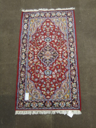 A contemporary red ground and floral patterned Eastern rug 66" x 36"