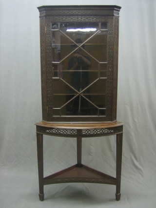 A Chippendale style corner cabinet the interior fitted shelves enclosed by astragal glazed panelled doors and with blind fret work decoration throughout, raised on a bow front base with undertier, raised on square tapering supports ending in spade feet 27"