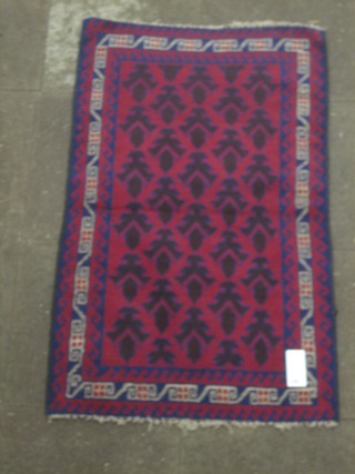 A contemporary red ground Belouch rug with stylised fern to the centre 50" x 31"