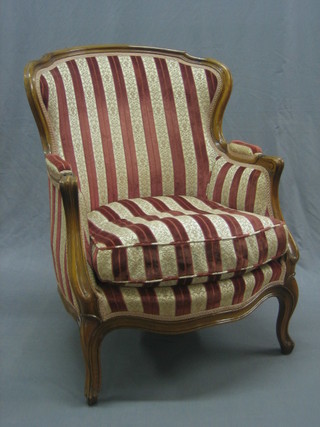 A French walnut show frame armchair upholstered in striped material, raised on cabriole supports