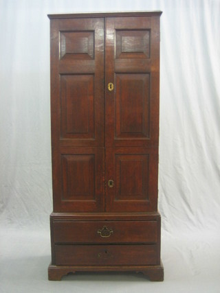 An 18th Century oak panelled estate cabinet, the interior fitted shelves and drawers enclosed by double panelled doors, the base fitted 1 long drawer, raised on bracket feet 25"