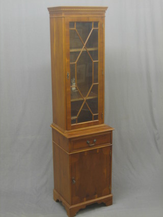 A Georgian style yew cabinet on cabinet with moulded and dentil cornice, the upper shelved interior enclosed by astragal glazed panelled door, the base fitted 1 long drawer above a cupboard enclosed by a panelled door, raised on bracket feet 19"