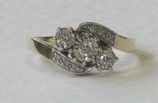 A 9ct gold cross-over dress ring set 3 diamonds and supported by 6 diamonds to the shoulders