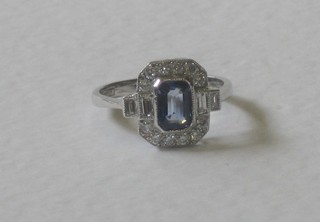 An 18ct white gold dress ring set a lozenge shaped sapphire and surrounded by numerous diamonds, approx 0.40/0.90ct