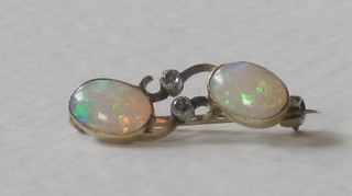 A gold bar brooch set 2 oval cut opals supported by 2 diamonds