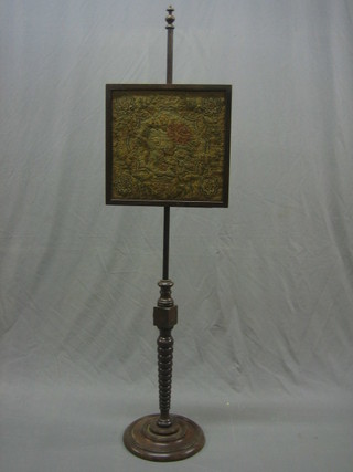 A Victorian pole screen with square frame containing a needlework panel, raised on a turned column