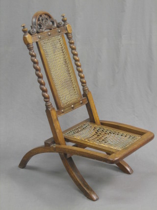 A 19th Century carved walnut folding chair with woven cane seat and back and spiral turned decoration to the sides