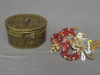 A pierced oval brass trinket box containing a collection of costume jewellery