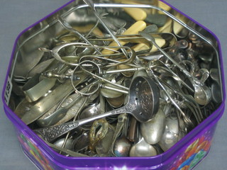 A Quality Street tin containing various teaspoons, tongs etc