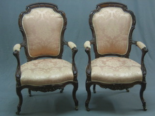 A pair of 19th Century Continental mahogany open arm chairs upholstered in pink material raised on cabriole supports