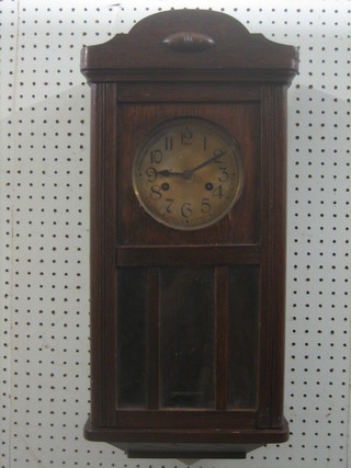 A 1930's striking hanging wall clock with silvered dial contained in an oak case