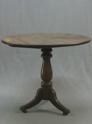 A 19th Century mahogany circular snap top tea table, raised on a turned and tripod base ending in brass caps and castors, 33"