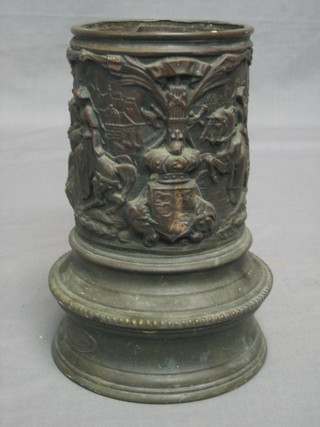 A circular Continental stick/umbrella stand with embossed decoration, decorated courtly figures and coats of arms, the base marked Erevet Dinedeniton 8"