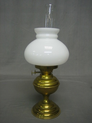 A brass oil lamp with opaque shade and clear glass chimney