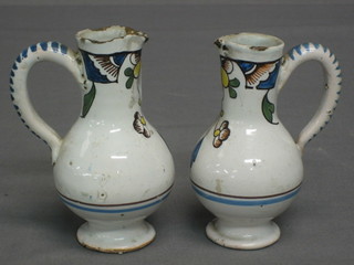 A pair of 18th/19th Century Delft jugs with floral decoration raised on spreading feet 4 1/2" (some chips)