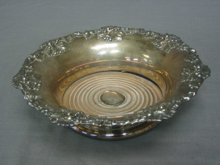 A circular silver plated bottle coaster with vine leaf border