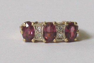 An 18ct yellow gold dress ring set 3 oval cut purple coloured stones supported by 4 diamonds