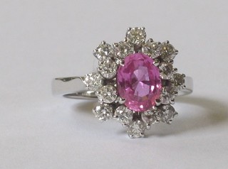 An 18ct white gold dress ring set an oval pink sapphire surrounded by diamonds