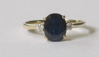 An 18ct gold dress ring set an oval cut sapphire supported by 2 diamonds