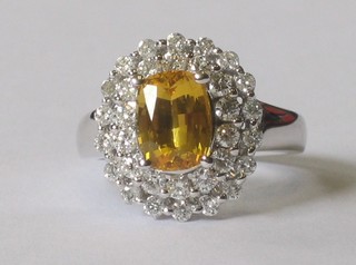 An 18ct white gold dress ring set an oval cut yellow sapphire surrounded by 2 rows of diamonds