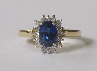 An 18ct yellow gold dress ring set an oval cut blue sapphire supported by diamonds