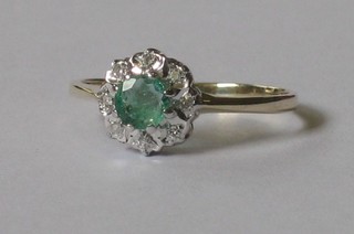 An 18ct yellow gold dress ring set a circular cut emerald supported by diamonds