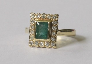 An 18ct yellow gold dress ring set a rectangular emerald surrounded by diamonds