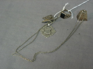 A silver watch chain medallion, a silver locket, a silver ring and a chain hung a charm in the form of a bird