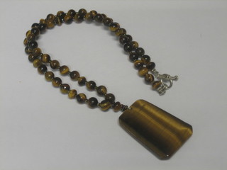 A lozenge shaped Tigers Eye pendant hung on a string of Tigers Eye beads