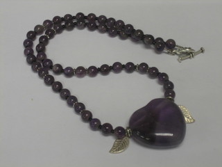 An "amethyst" heart shaped pendant hung on a string of beads