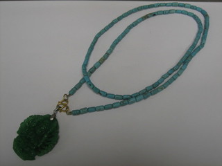 A jade coloured pendant hung on a turquoise chain