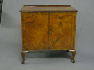 A Queen Anne style walnut cabinet with crossbanded top enclosed by panelled doors, raised on cabriole supports 30"
