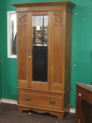An Edwardian bleached walnut wardrobe with moulded cornice enclosed by bevelled plate mirror door, the base fitted a drawer 42"