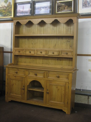 A 20th Century pine dresser with moulded and shaped cornice fitted shelves above 5 spice drawers, the base fitted 3 drawers above a recess flanked by double cupboards 66"