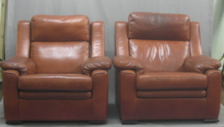 A pair of armchairs upholstered in brown leather