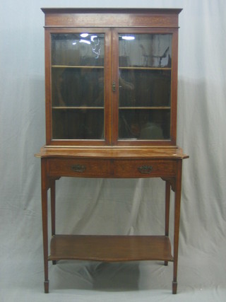 An Edwardian inlaid mahogany cabinet, fitted shelves enclosed by glazed panelled doors, the base of serpentine outline fitted 2 drawers raised on square tapering supports ending in spade feet with undertier 35"
