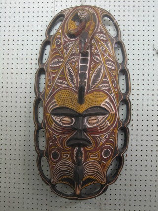 An Eastern (Papua New Guinea?)  oval carved and painted wall mask with snake decoration, the eyes set shells 28"