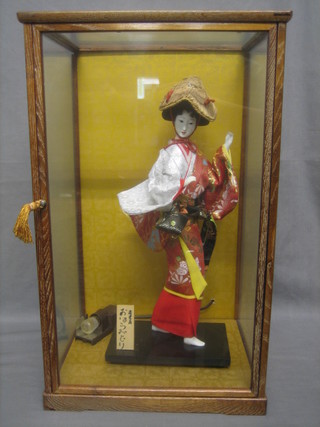 A Japanese figure of a doll contained in a glazed display cabinet 21"