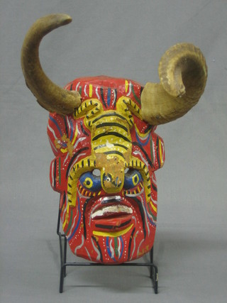 A carved wooden and painted mask with horn decoration 12"