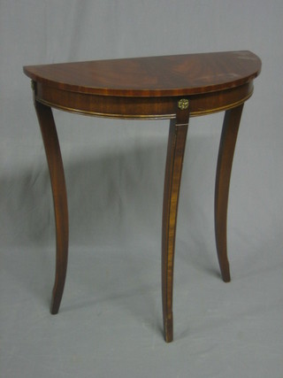 A mahogany demi-lune hall table with cross banded top raised on sabre supports 24"