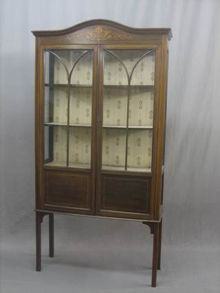 An Edwardian inlaid mahogany display cabinet enclosed by glazed panelled doors, raised on square tapering supports 36"