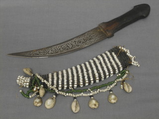 An Eastern dagger with etched blade 6" contained in a shell and bead covered scabbard