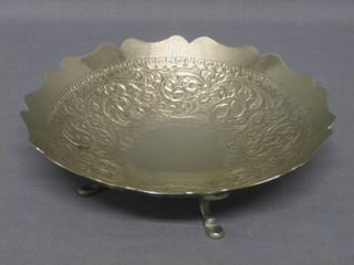 A circular Eastern embossed white metal dish raised on 4 scallop feet 7 1/2 ozs