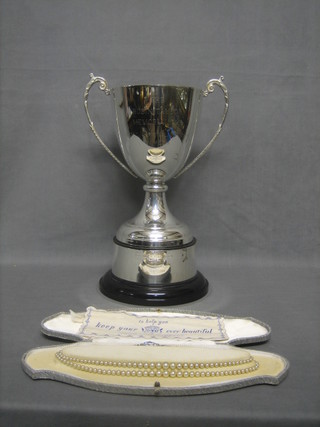 A silver plated twin handled trophy cup, a half crown mounted pendant and a string of cultured pearls