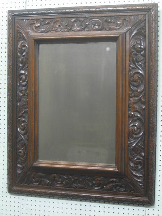 A 19th Century rectangular plate mirror contained in a heavily carved oak cushion shaped frame 33"