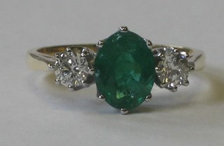 An 18ct yellow gold dress ring set an oval cut emerald supported by 2 diamonds approx 0.5/1.50ct