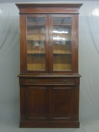 A Victorian mahogany bookcase on cabinet, the upper section with moulded cornice the interior fitted adjustable shelves enclosed by panelled doors, the base fitted 1 long drawer above a double cupboard, raised on a platform base 41"