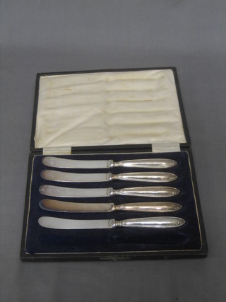 A set of 5 silver handled tea knives, cased